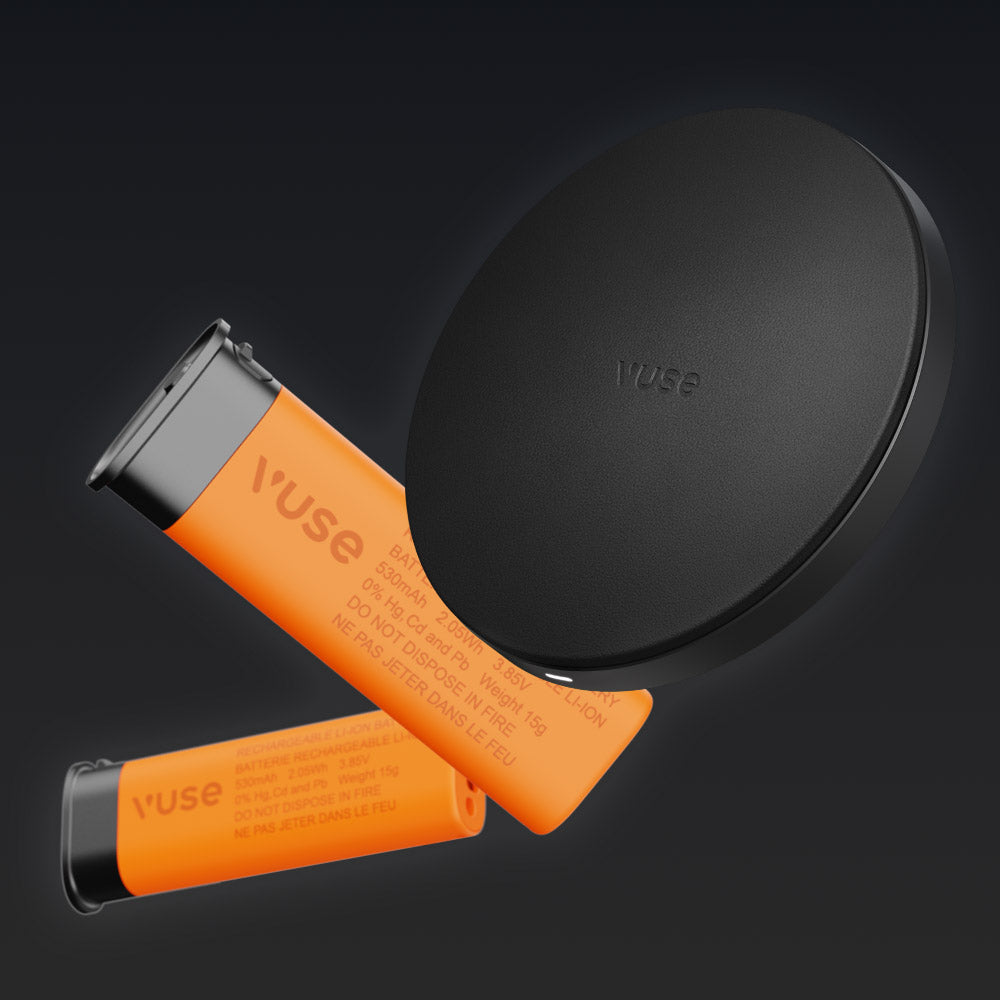 Two orange Vuse pods with black caps sit next to a round black Vuse Ultra Device Kit McLaren case against a dark background. Warning text is visible, highlighting the advanced vape experience from Vuse.